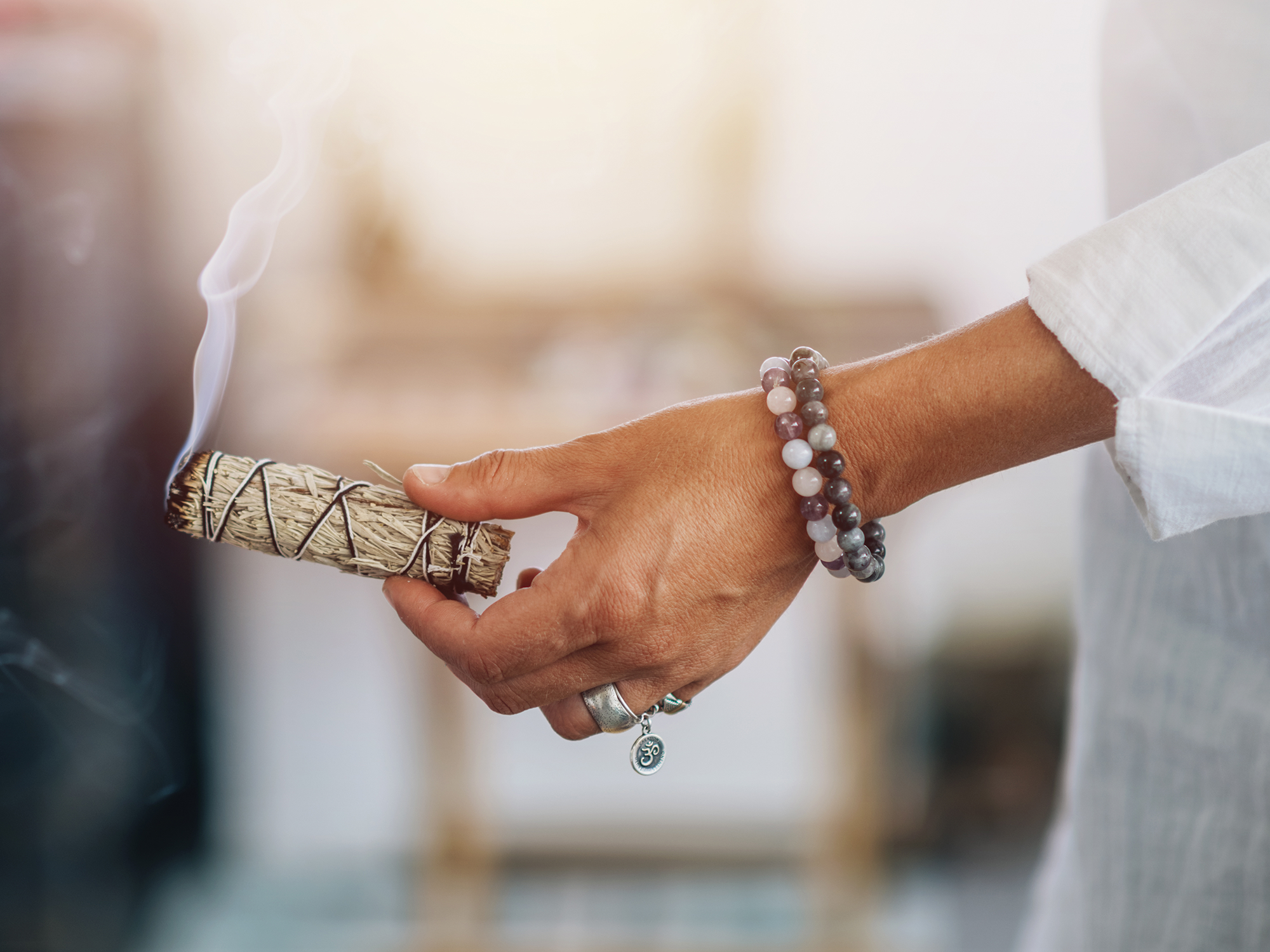 Hand holding a smoking sage bundle