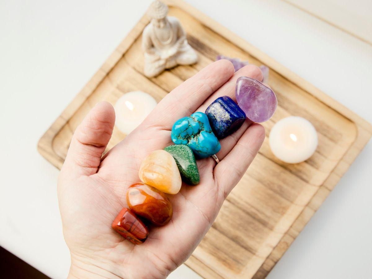 Hand holding 7 tunneled crystal in the color of the chakras