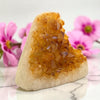 Crystal rock with a honeycomb-like interior on a marble surface with pink flowers in the background
