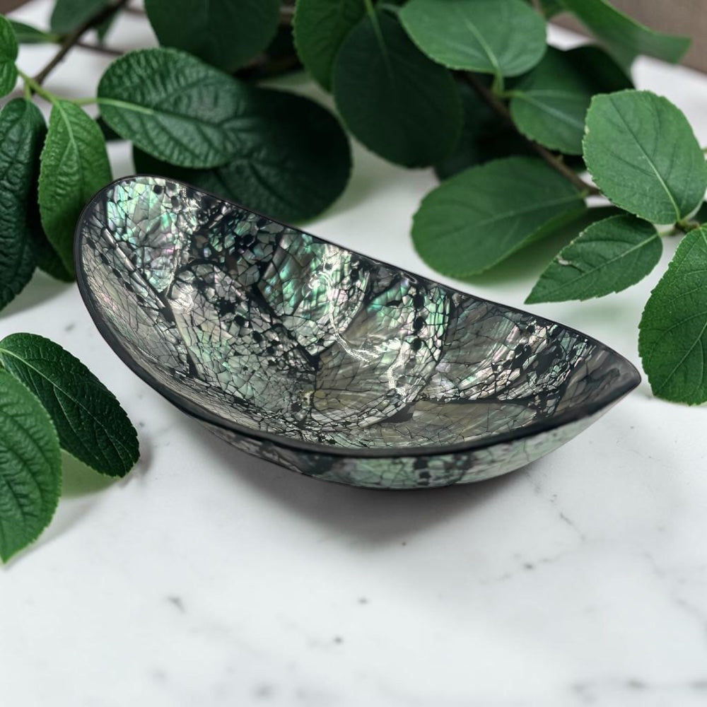 Decorative shell bowl on a marble surface with green leaves