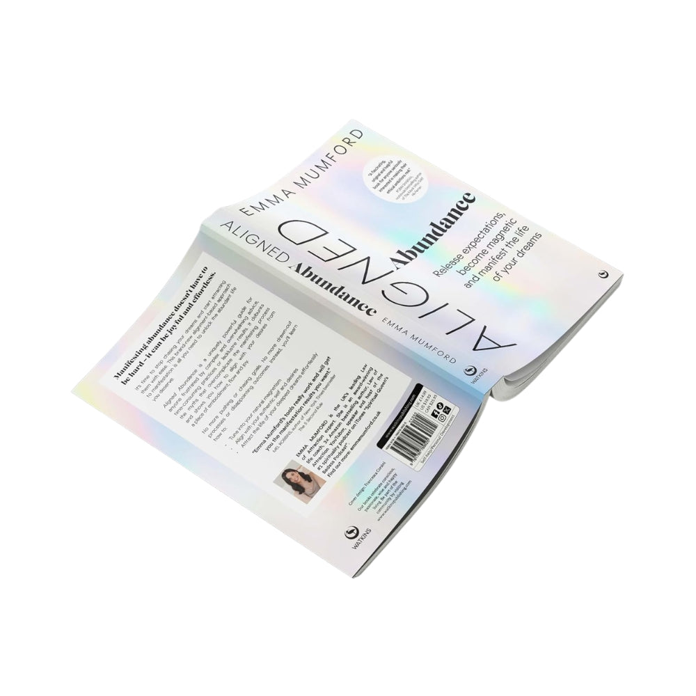 An open book titled 'Aligned' by Emma Mumford, displayed against a solid white background. The book features a white cover with a subtle iridescent rainbow sheen and black typography.