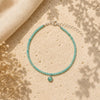 Turquoise beaded bracelet with a silver clasp on a beige surface with dried flowers.