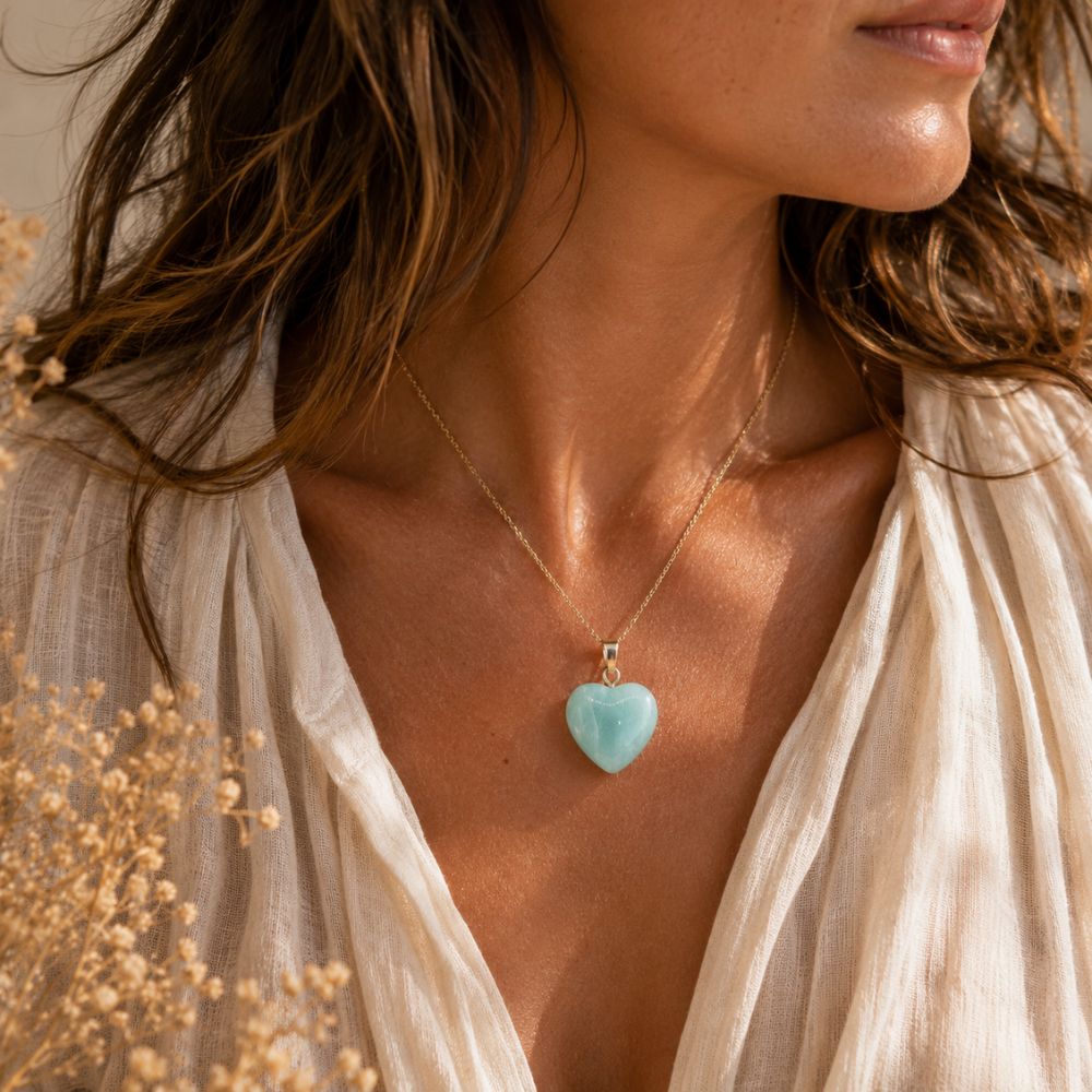Woman wearing a necklace with a heart-shaped pendant, surrounded by beige flowers.