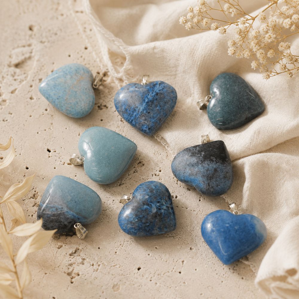 Heart-shaped blue stones on a beige fabric background with dried flowers.