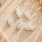 Aura clear quartz point pendants displayed on a warm natural stone surface, showing the unique shape, size, and iridescent finish of each crystal.