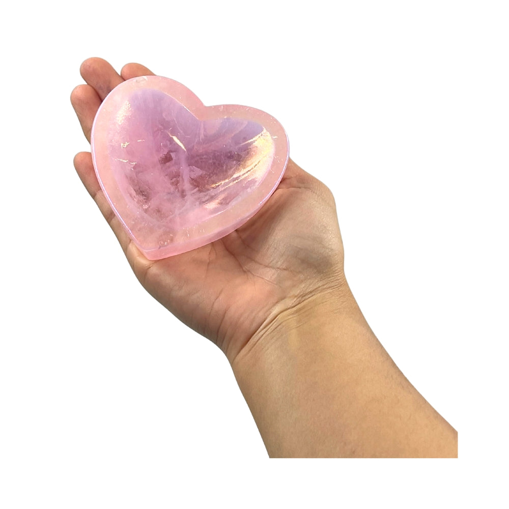 Hand holding a pink heart-shaped Rose Quartz Dish against a white background