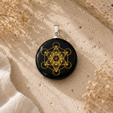 Black Obsidian Metatron Pendant with gold sacred geometry symbol on a polished round black stone.