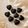 Black heart-shaped pendants on a beige fabric background with dried flowers.