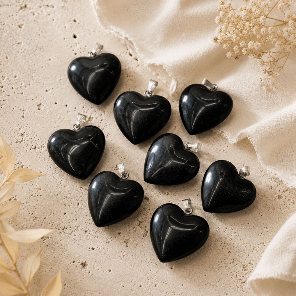 Black heart-shaped pendants on a beige fabric background with dried flowers.