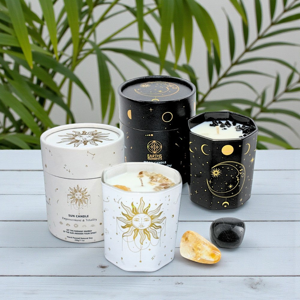 Candles with celestial designs on a wooden surface with plants in the background