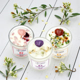 Three crystal candles on a white wooden surface with floral decorations.