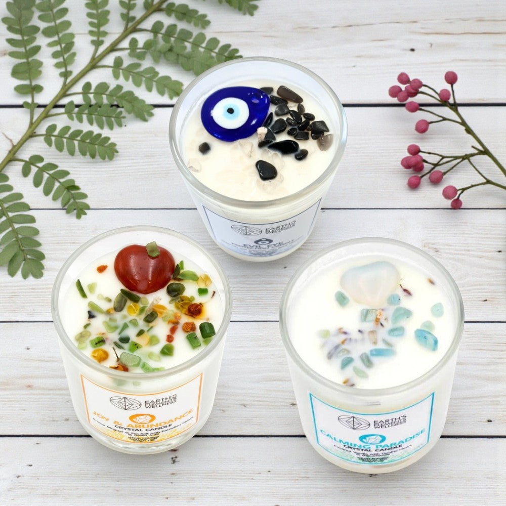 Three decorative candles with unique designs on a wooden surface with plants.