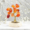 Decorative tree sculpture with orange and red stones on a marble base, against a neutral background.