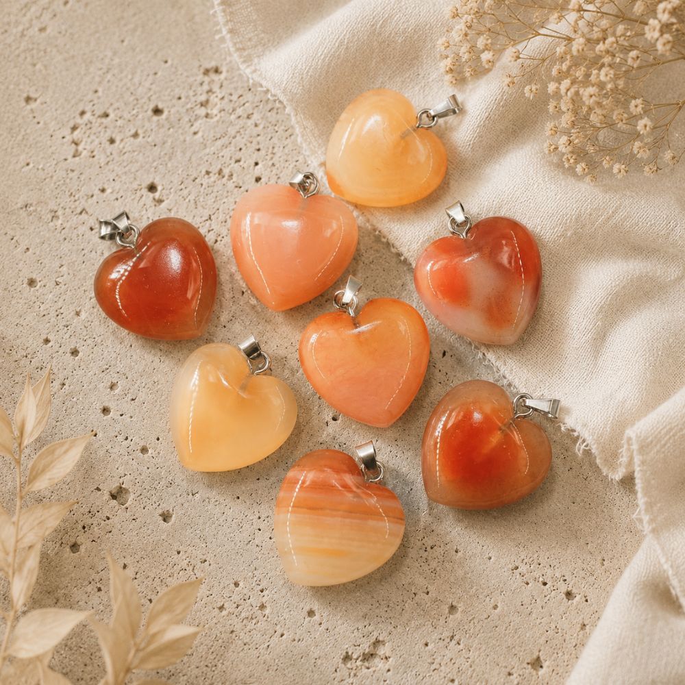Heart-shaped stone pendants on a textured beige surface with dried flowers.
