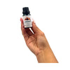 Hand holding a bottle of cinnamon essential oil against a white background