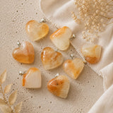 Heart-shaped stone pendants on a textured beige surface with dried flowers.