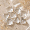 Clear heart-shaped objects on a textured beige surface with dried flowers.