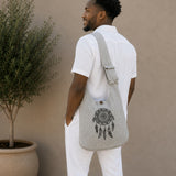 Man wearing a gray bag with a dreamcatcher design against a beige wall.