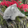Howlitedolphin figurine on a tree branch with pink flowers in the background