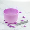 Purple singing bowl with flowers on a marble surface