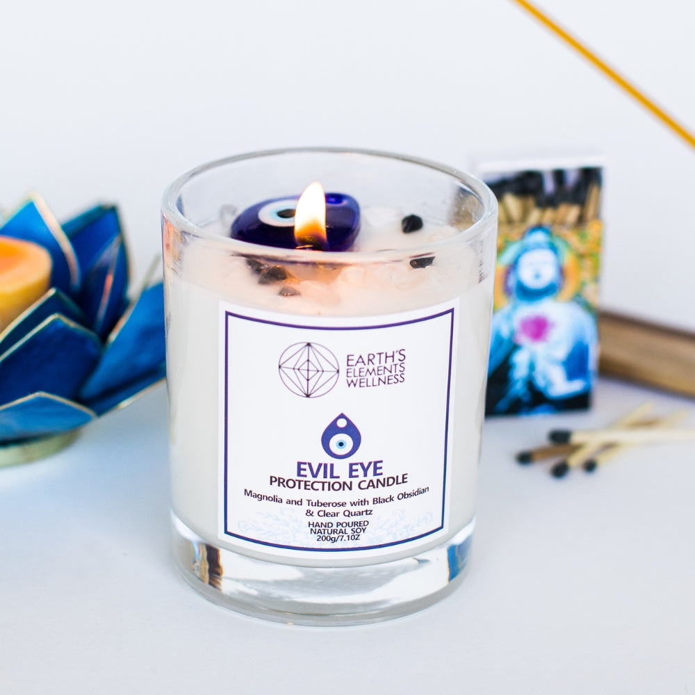 Candle in a glass jar with a label on a white surface, surrounded by decorative items.