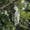 Dreamcatcher with yin yang symbol hanging from a tree branch with flowers.