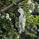 Dreamcatcher with yin yang symbol hanging from a tree branch with flowers.