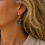 Close-up of a person wearing a decorative earring with a crescent moon design.