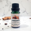 Bottle of cinnamon essential oil with cinnamon sticks on a marble background