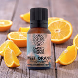 Bottle of Earth's Elements Wellness Sweet Orange essential oil surrounded by sliced oranges on a wooden surface.