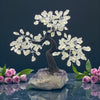 Decorative crystal tree on a rock with pink roses against a dark background