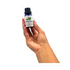 Hand holding a bottle of French Basil essential oil against a white background