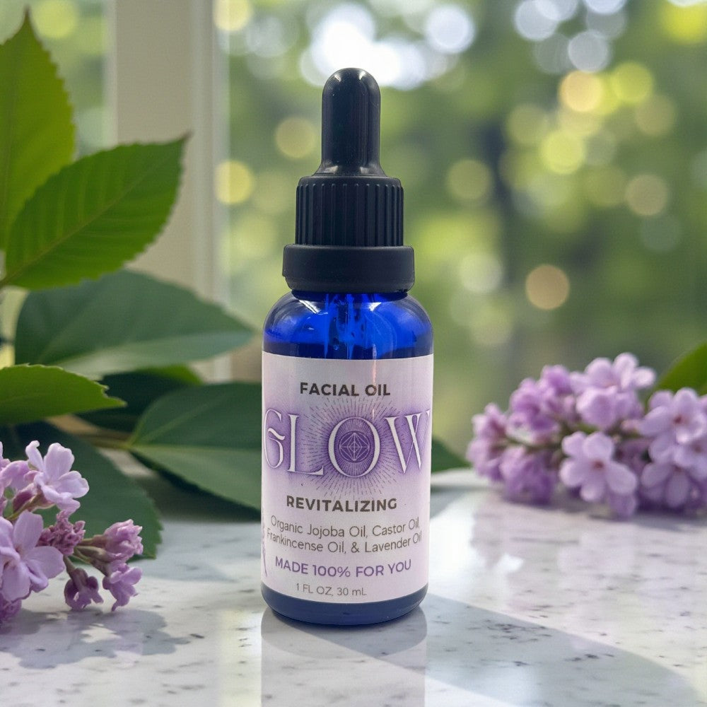 Facial oil bottle labeled 'GLOW' with flowers on a marble surface