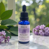 Facial oil bottle labeled 'GLOW' with flowers on a marble surface