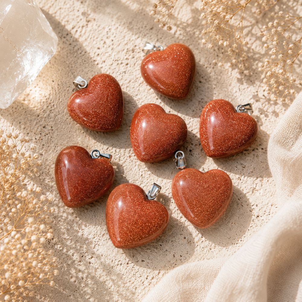 Goldstone Mini Heart Pendants with shimmering copper sparkles on a warm limestone surface with linen and dried florals.