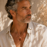 Man wearing a Goldstone Mini Heart Pendant necklace in warm natural sunlight.