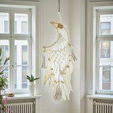 Decorative dreamcatcher hanging in a room with windows and a radiator.