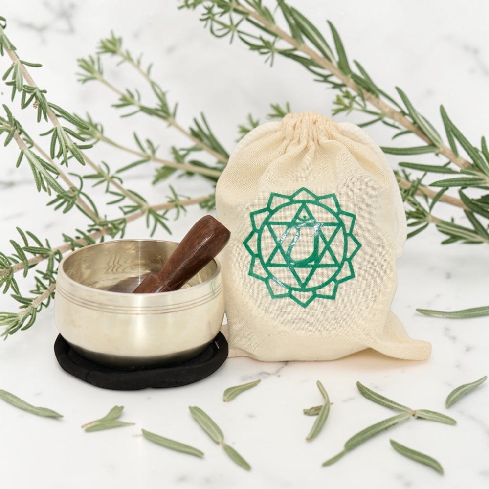 Heart Chakra Singing Bowl in Pouch on a white background with rosemary leaves.