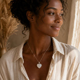 Woman wearing a Snow Quartz heart pendant necklace with a casual neutral outfit. 🌿