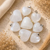 Snow Quartz heart crystal pendants with silver and gold bails on a neutral textured background.