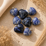 Sodalite heart crystal pendants with silver bails on a neutral textured background.