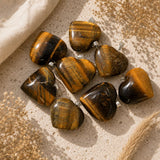 Tiger's Eye heart crystal pendants with silver bails on a neutral textured background.