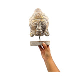 Decorative Buddha head sculpture held by a hand on a white background
