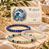 Three beaded stretch bracelets arranged on a burlap surface with a decorative card reading “Water” behind them. The bracelets include dark blue lapis lazuli, clear quartz, and amazonite.