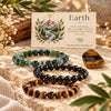 Three beaded stretch bracelets arranged on a stone surface with a small printed card behind them and a tiger's eye stone nearby. The bracelets are made of round beads they are moss agate, black obsidian, and tiger's eye.