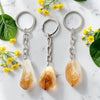 Three crystal keychains on a marble surface with yellow flowers and green leaves.