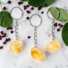Three Citrine keychains on a marble surface with green leaves and red berries.