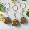 Three tiger eye keychains on a marble surface with flowers and leaves.