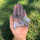 Hand holding Amethyst Aura keychains against a grass background