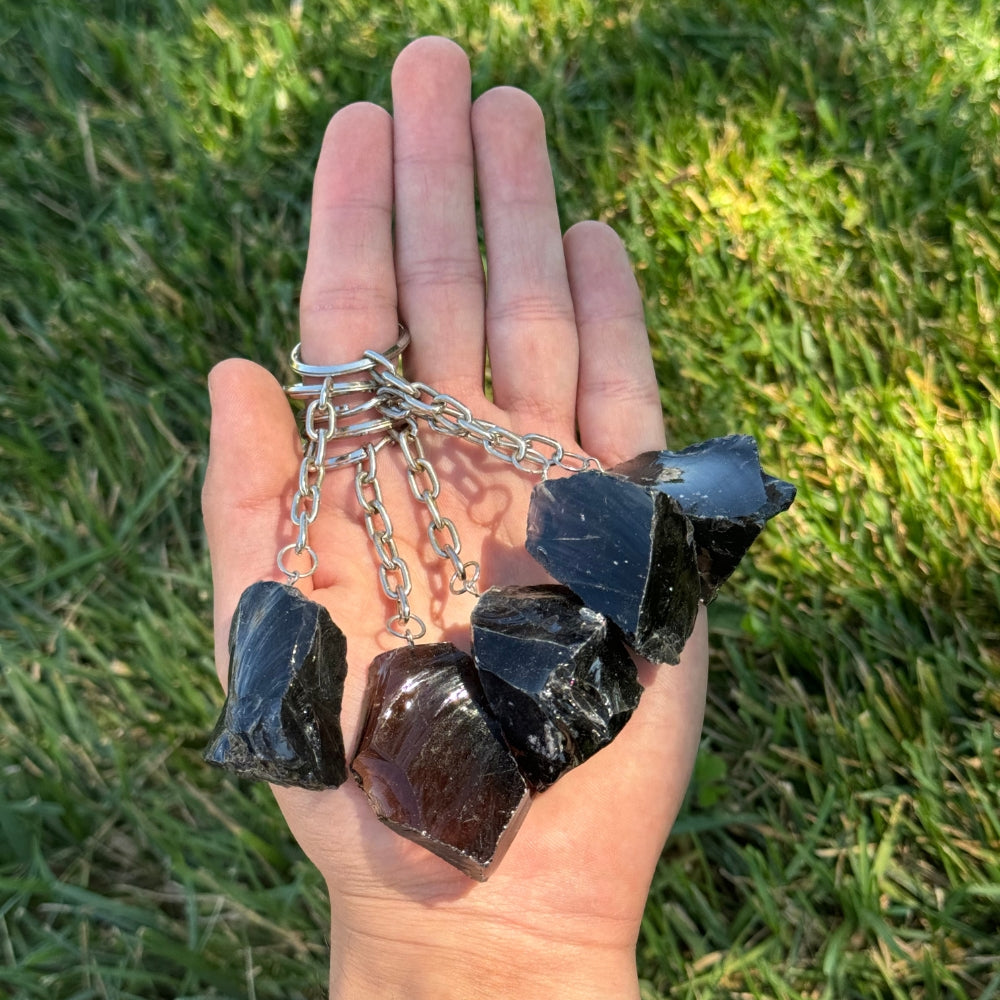Hand holding a Black Obsidian Keychainagainst a grassy background